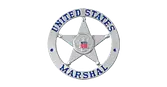 A silver badge with a five-pointed star in the center, displaying the words "United States Marshal" in blue letters around the star, and a small U.S. flag emblem in the middle.